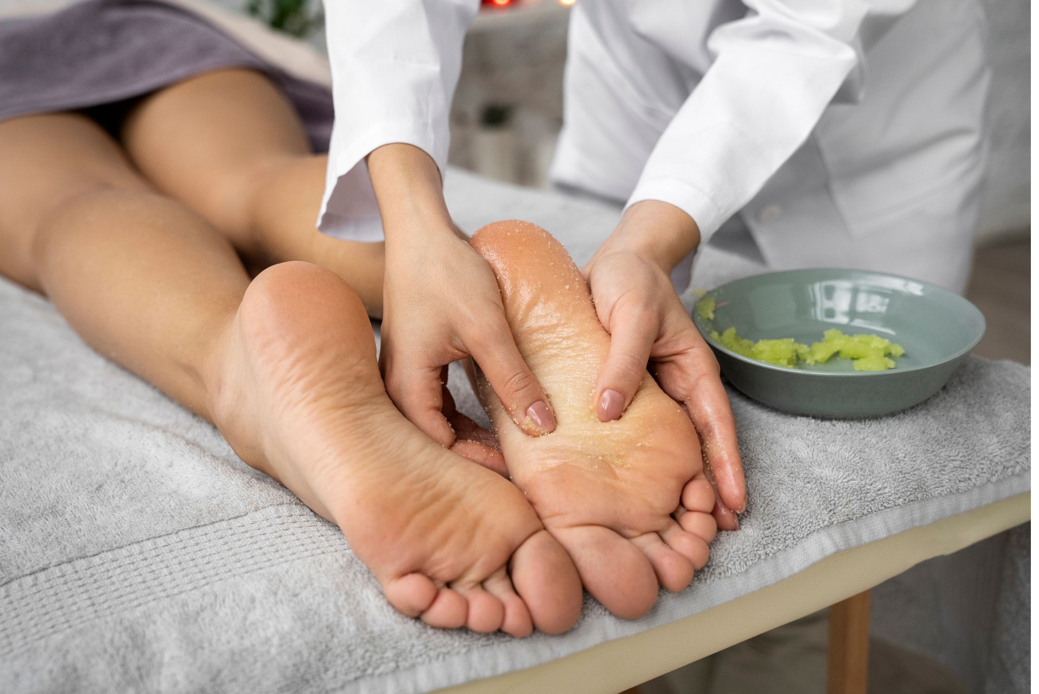 Profissional aplicando terapia de reflexologia nos pés do paciente durante sessão de tratamento